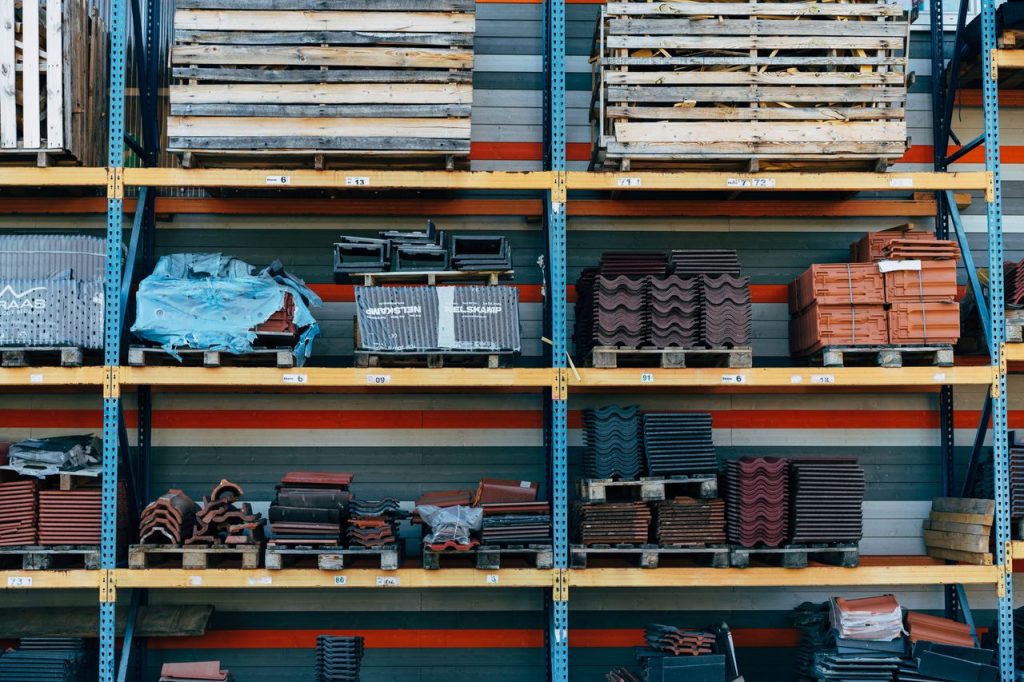 Shelves filled with construction materials like tiles and wood pallets in a warehouse setting.